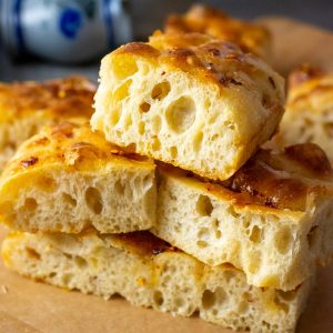 Hot honey sourdough focaccia cut into squares on a piece of parchment paper.