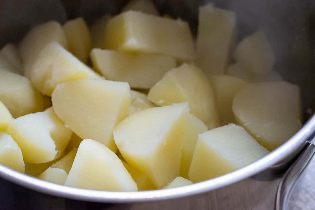 Boiled potatoes steaming in a colander.