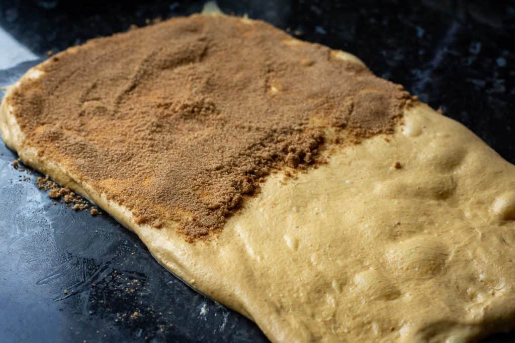 Pumpkin Pie Spice Sugar sprinkled across half of the stretched out sourdough .