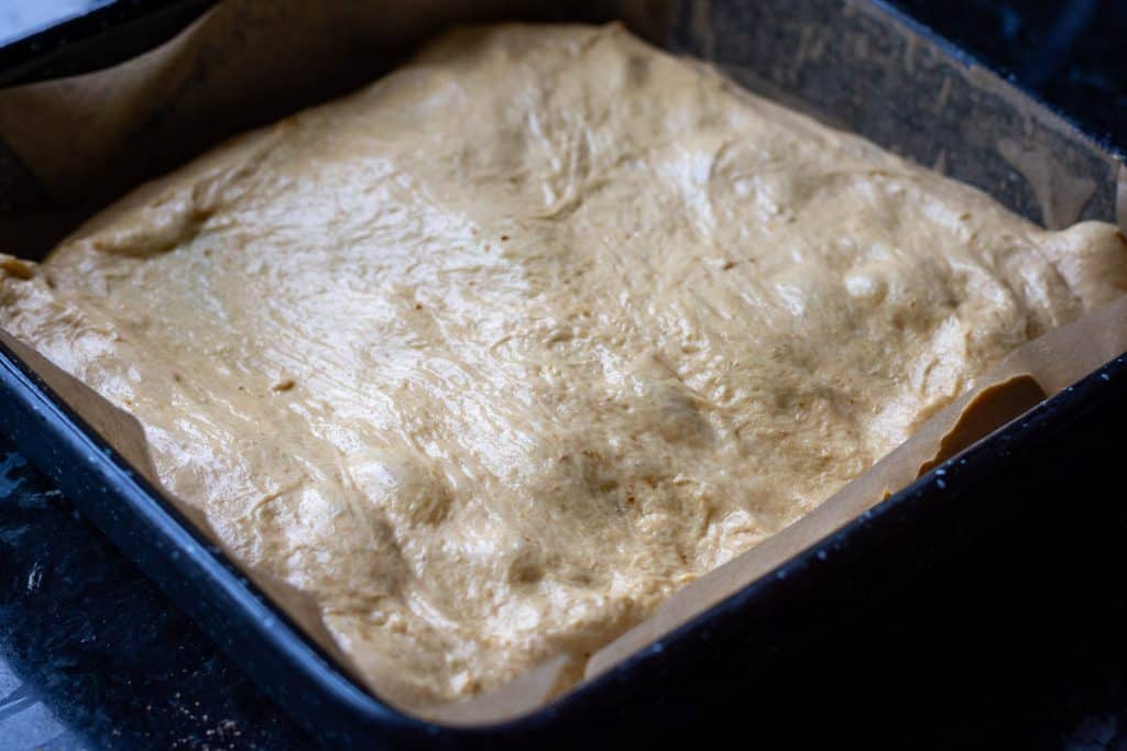 Pumpkin sourdough focaccia dough transferred into a high-rimmed baking tray.