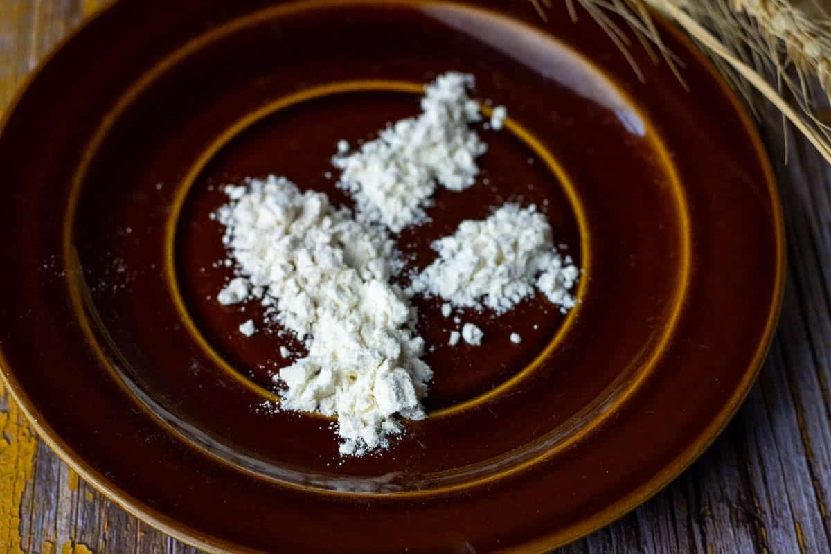 Four types of white flour on a brown plate.