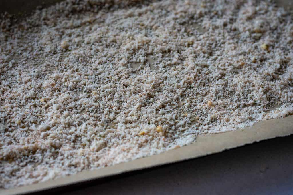 Parmesan Mixture scattered on the parchment paper lined baking tray.