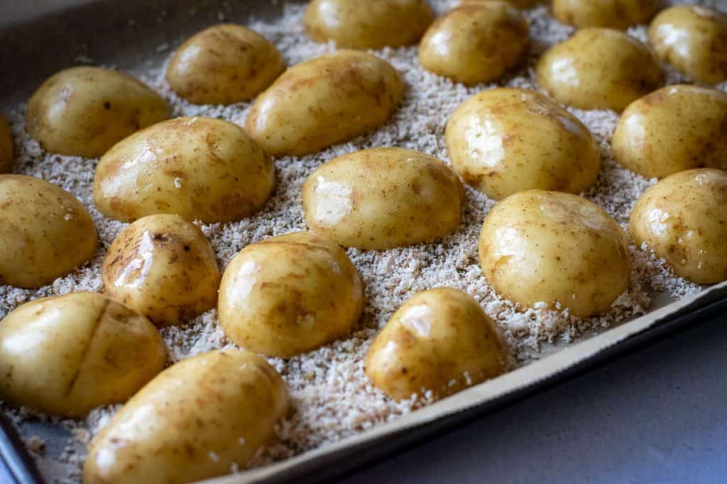 Halved baby potatoes arranged on the parmesan layer.