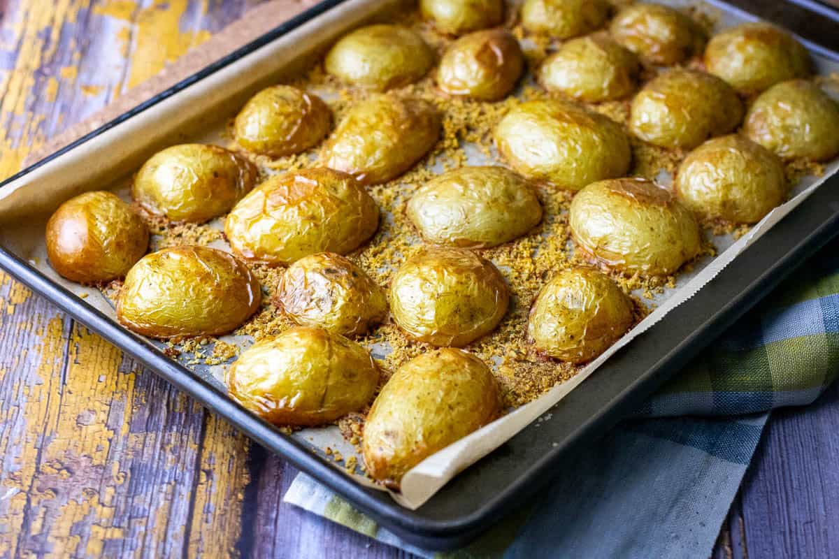 Roasted baby potatoes with parmesan cheese on a baking tray.