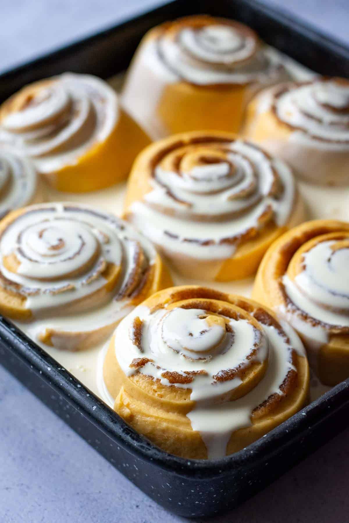 Cream poured over sourdough pumpkin cinnamon rolls.