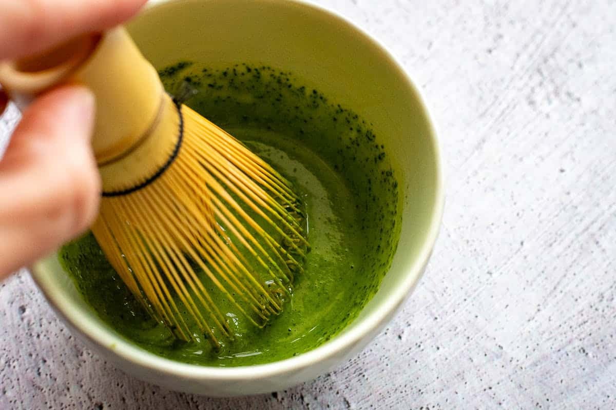 Whisking matcha with a small amount of cream mixture to prevent lumps.