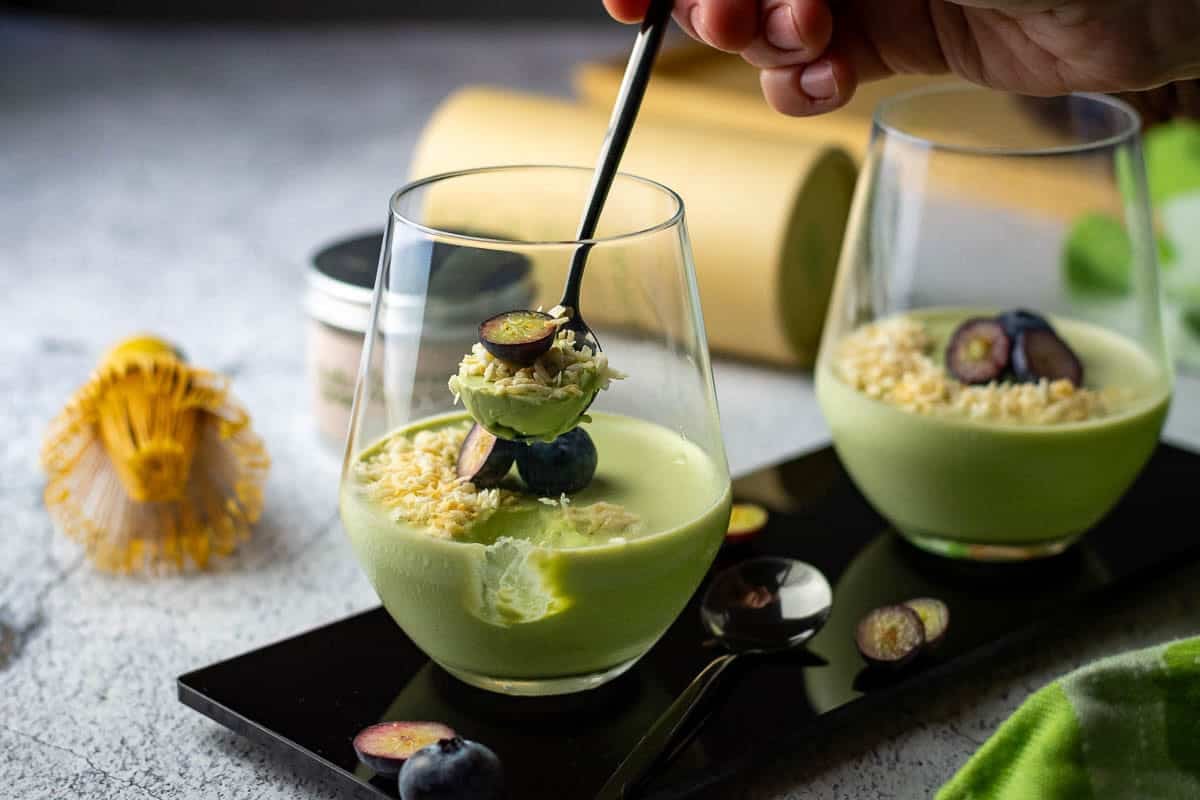 A spoonful of matcha panna cotta being taken out of the glass.