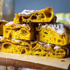 Sweet Pumpkin Sourdough Focaccia with alyers of spiced sugar cut into squares and stacked on a piece of parchment paper.