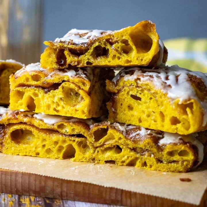 Sweet Pumpkin Sourdough Focaccia with alyers of spiced sugar cut into squares and stacked on a piece of parchment paper.
