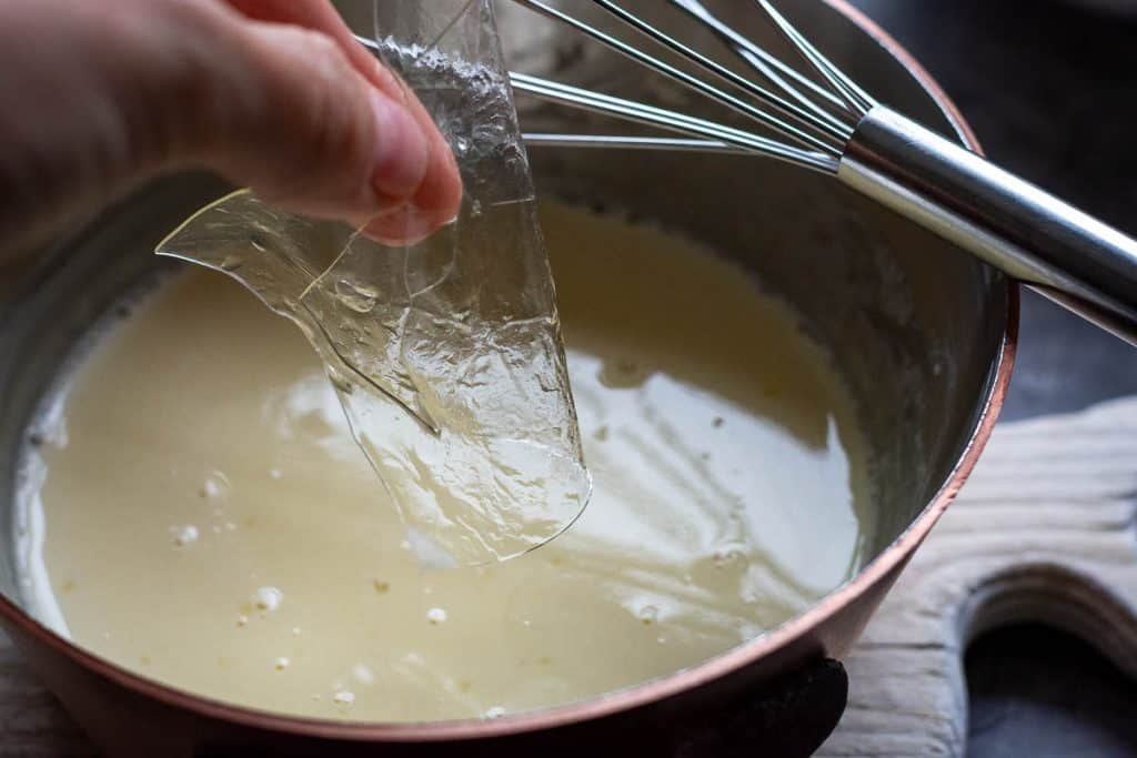 Adding softened gelatine to the hot cream mixture.