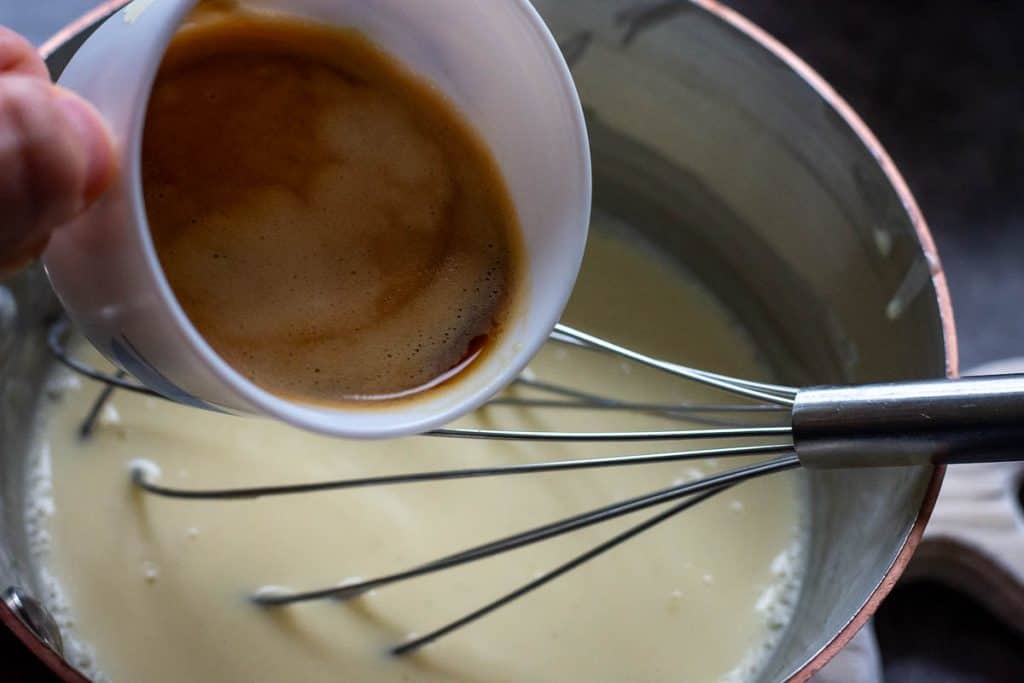 Pouring espresso coffee into the panna cotta mixture.