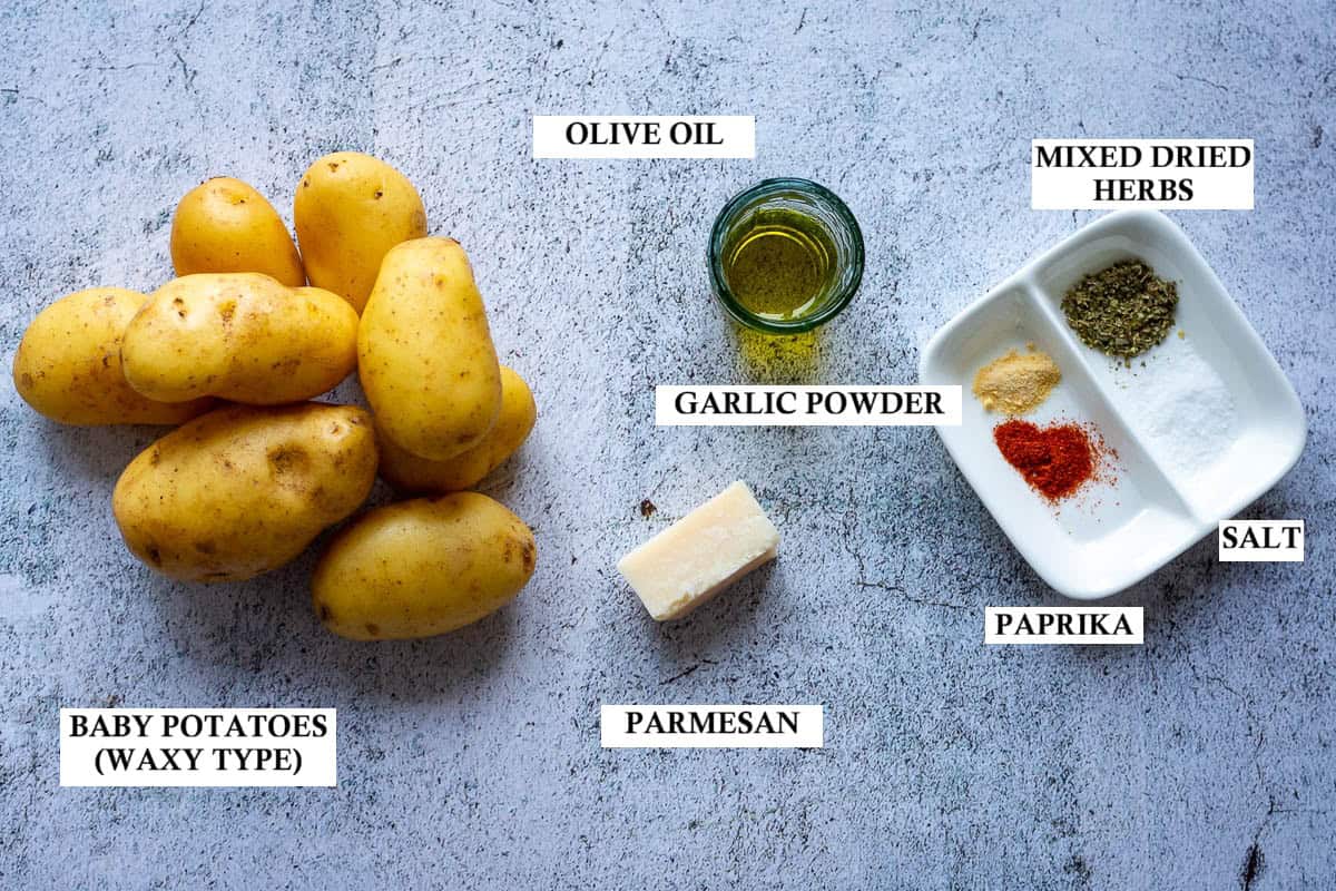 Ingredients for Smashed Potatoes with Parmesan Cheese on a light grey surface.