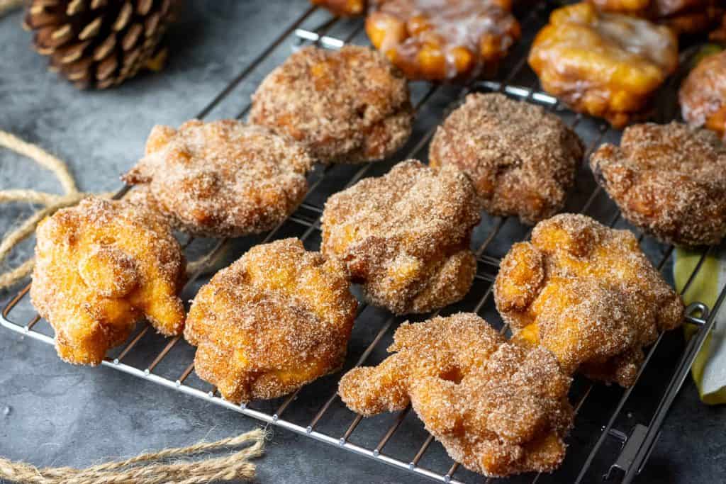Cinnamon Sugar coated Sourdough Apple Fritters on a wire rack.