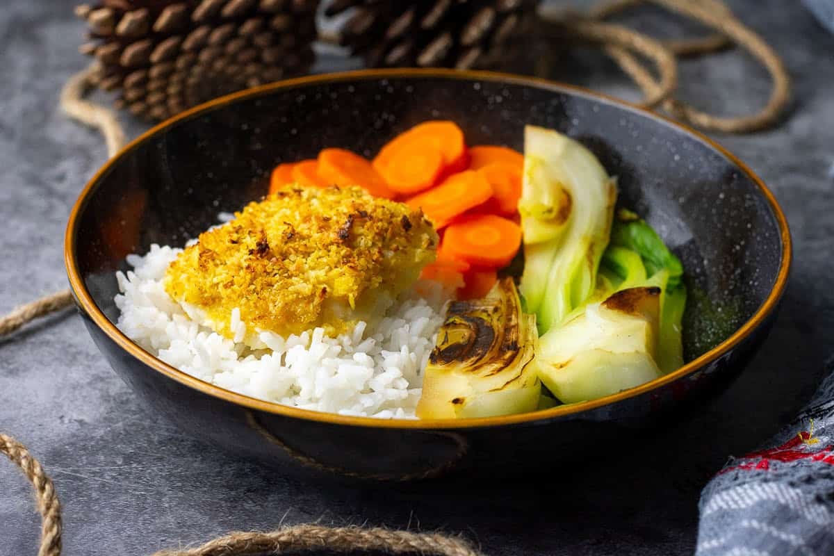 Coconut crusted cod on a bed of rice served with pak choi and carrots.