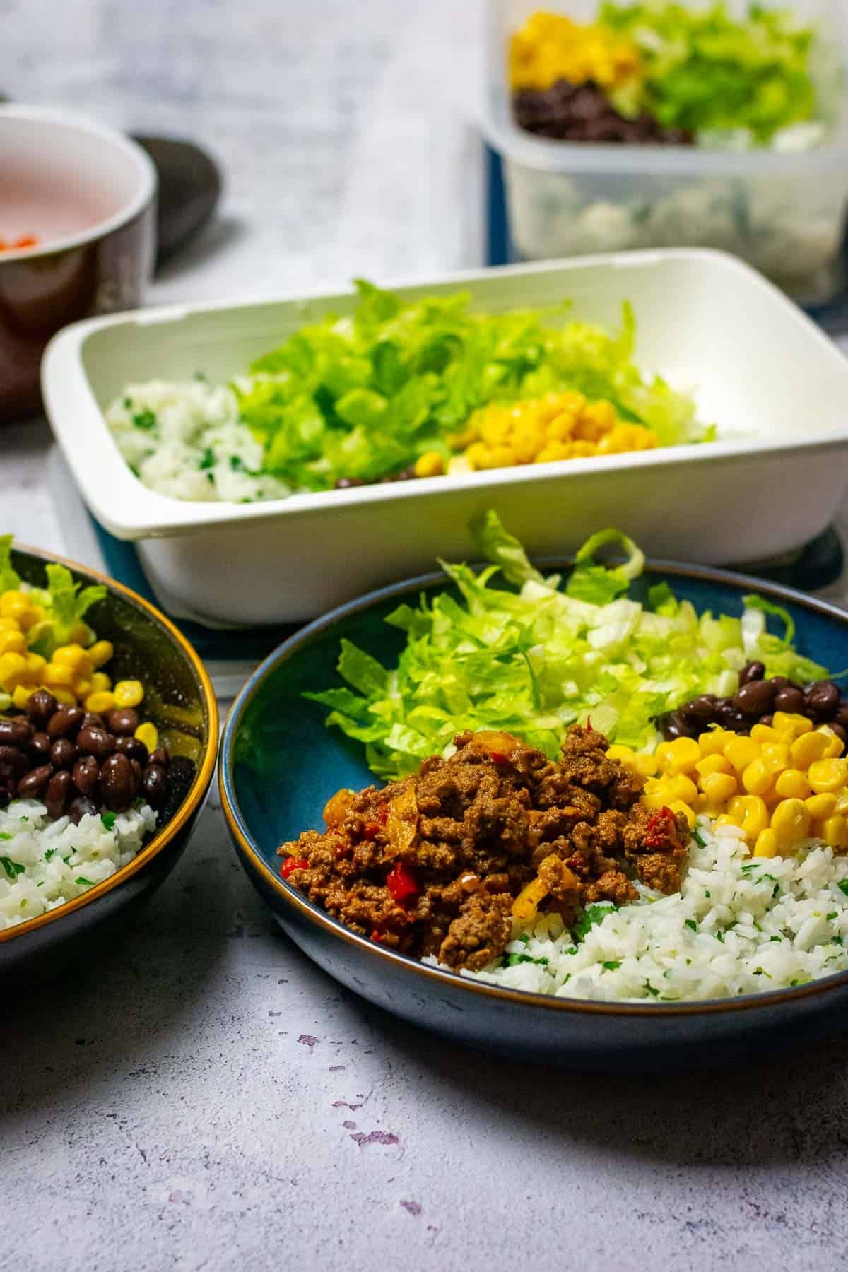 Two bowls of beef burrito salad and a Tupperware box ready to lunch tomorrow.