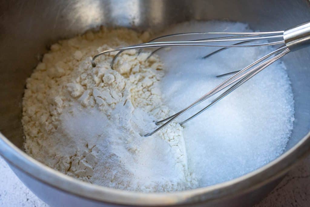 Combining dry ingredients in a large metal bowl.
