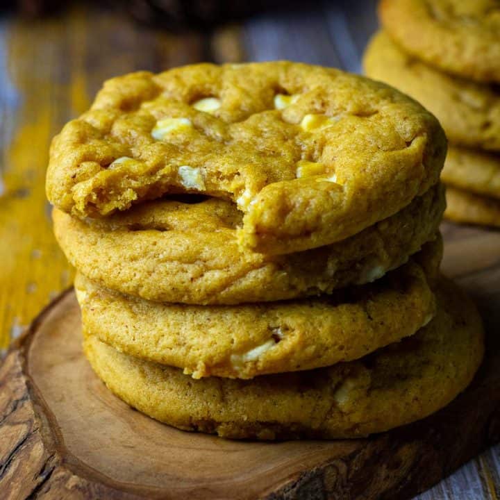 Stacks of Sourdough Pumpkin Cookies with chocolate chips with one bitten into.