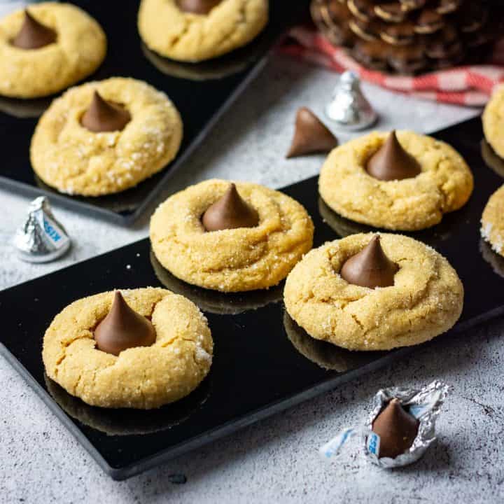 Sourdough Peanut Butter Blossoms arranged on black serving boards with chocolate kisses scattered around.