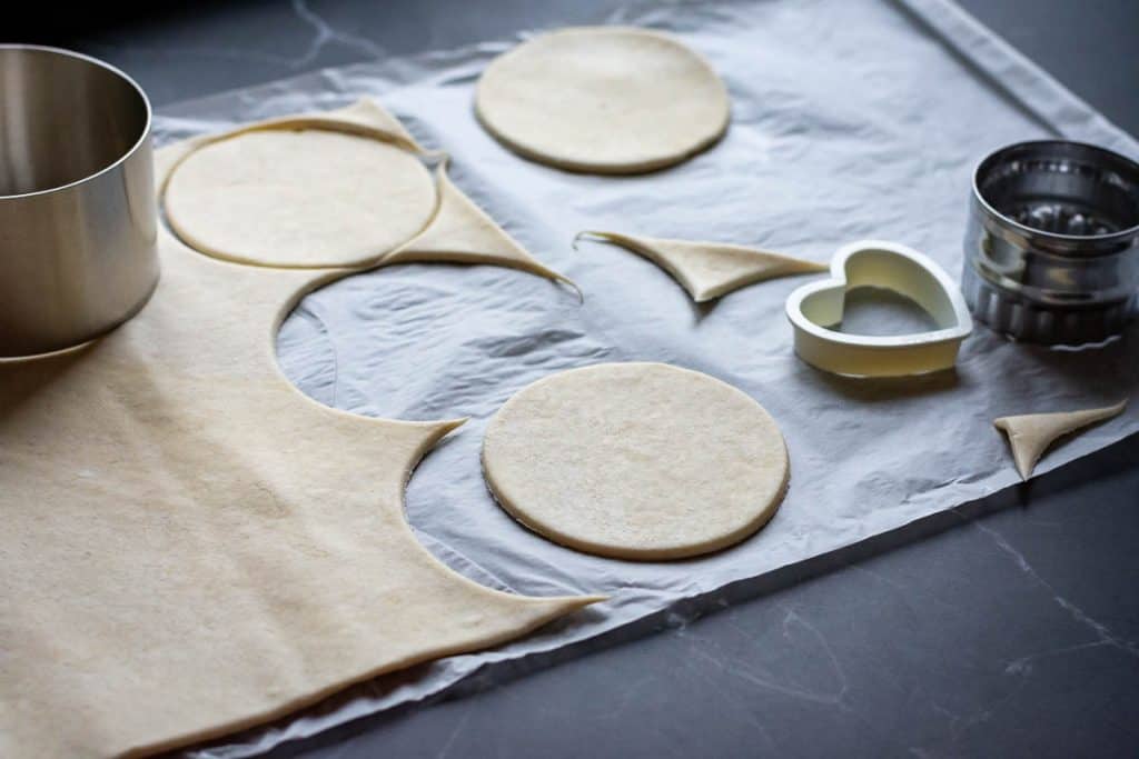 Stamping out cirlces of puff pastry with a large cookie cutter.