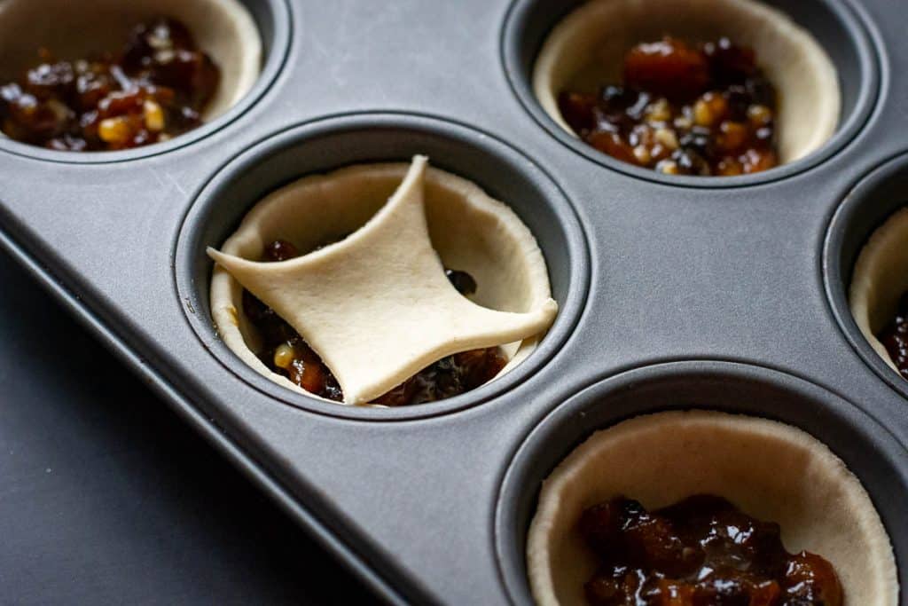A diamond shaped puff pastry scrap on top of a mince pie.