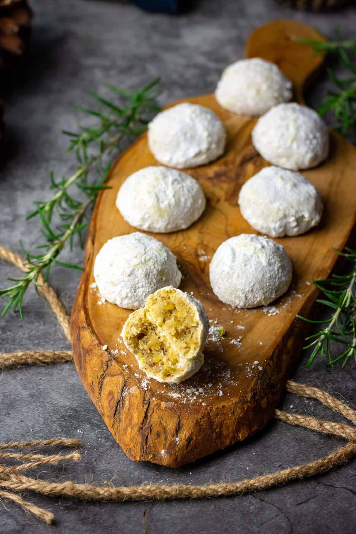 Sourdough Snowball Cookies on a decorative wooden board with one cookie broken up in half.