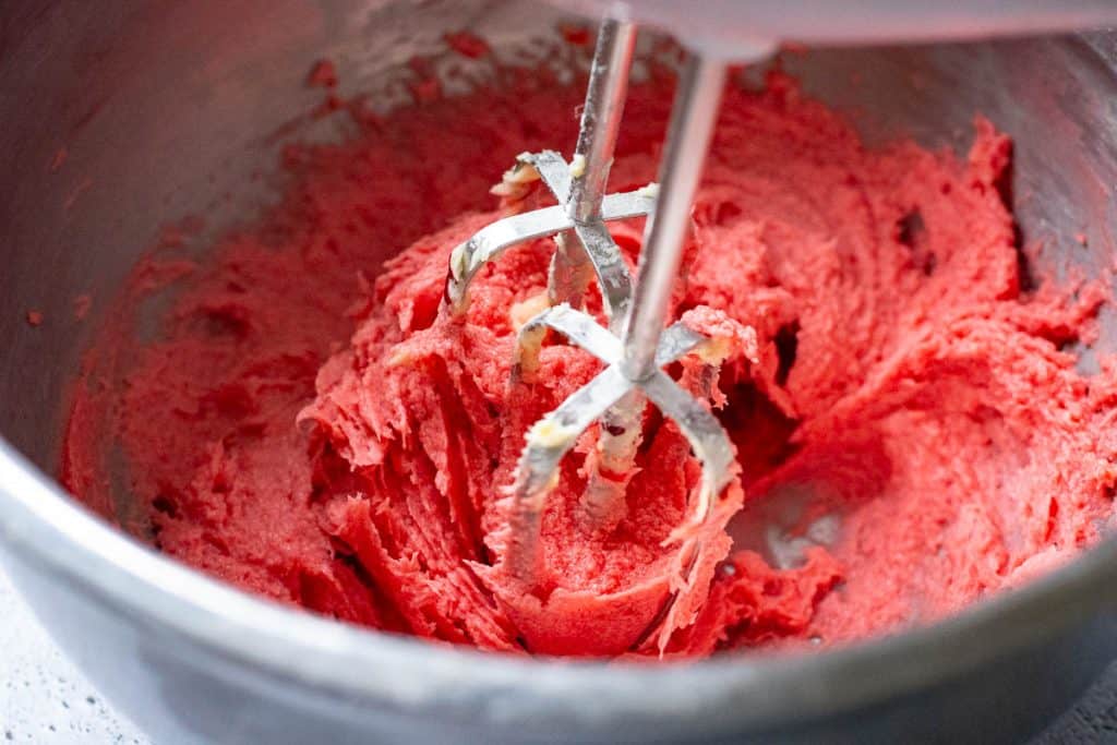Red thumbprint cookie batter being creamed.