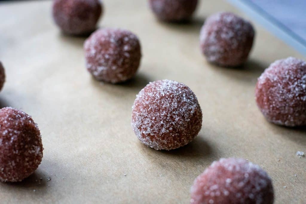 Sourdough cookie balls arranged on a parchment paper lined baking sheet.