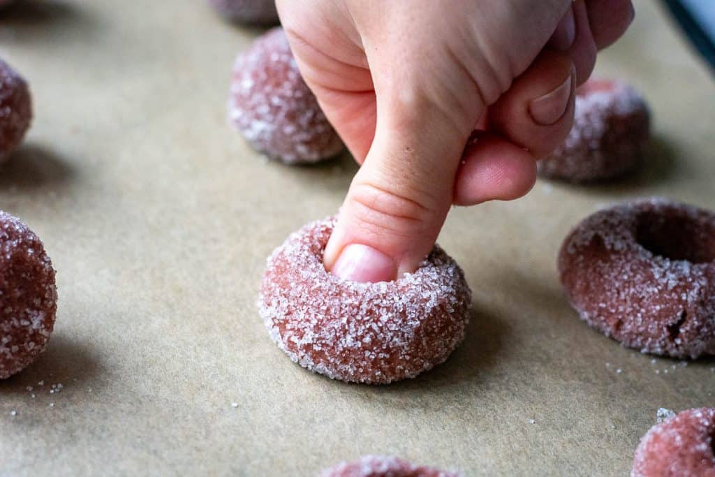 Pressing a thumb into the centre of each sourdough cookie ball.