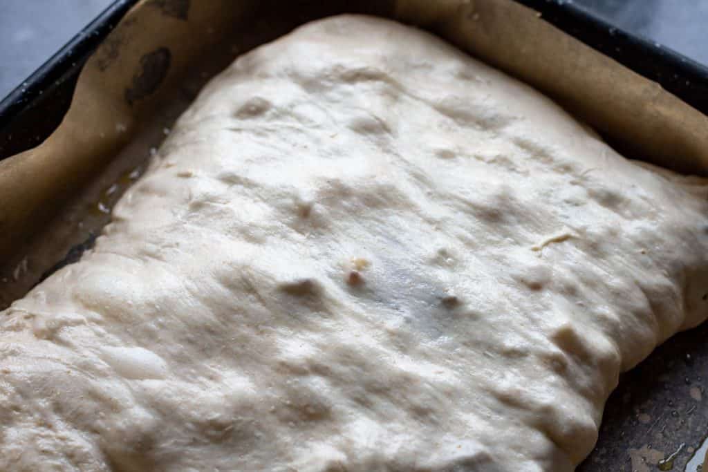Sourdough folded over the stollen filings in a high-rimmed baking tray.