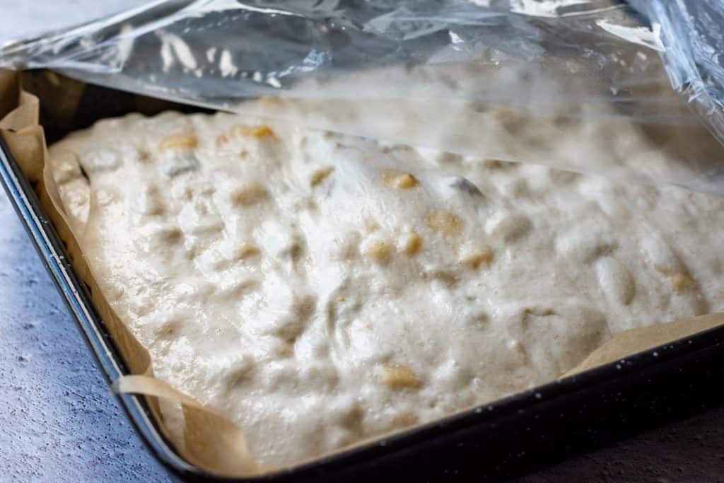Sourdough stollen focaccia covered with cling film for second rise.
