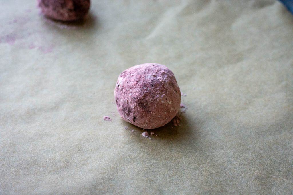 Sourdough chocolate crinkle cookie dough ball rolled in pink powdered sugar made with beetroot powder.
