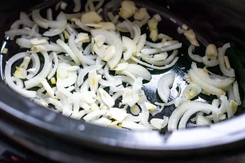 Onions and garlic on the base of the slow cooker.