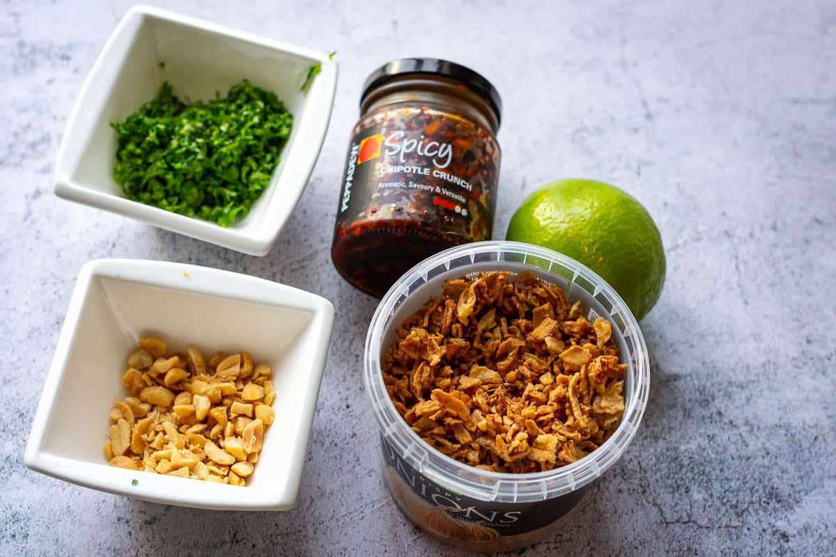 Selection of toppings for the soup including peanuts, crispy onions, crunchy chilli and herbs.