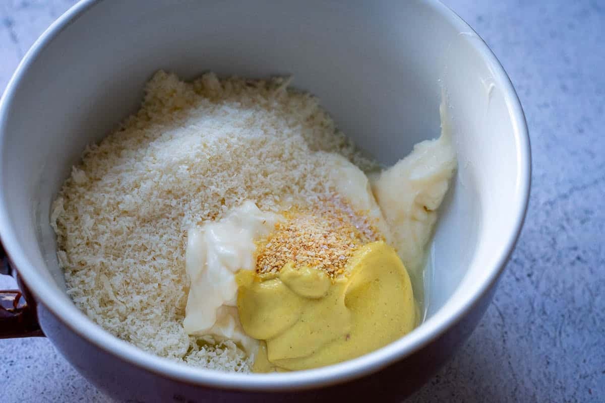 Ingredients for homemade caesar salad dressing in a white bowl.