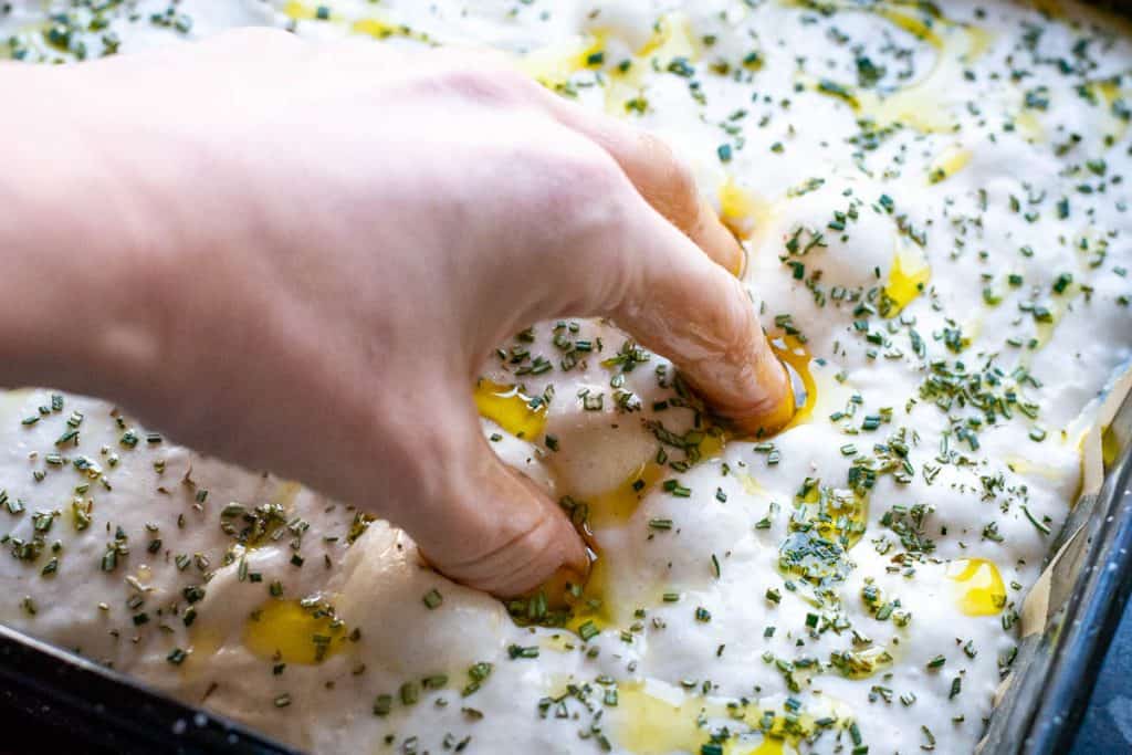 Dimpling focaccia with oiled fingers.