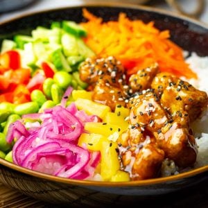 Teriyaki Tofu Poke Bowl served in a black bowl, with sesame seeds sprinkled on top.