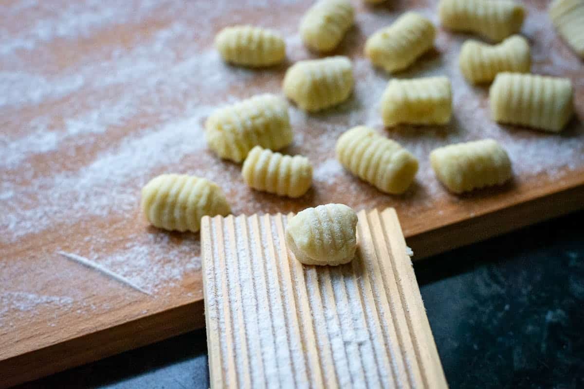 Rolling gnocch on a wooden board with ridges to create their unique shape.
