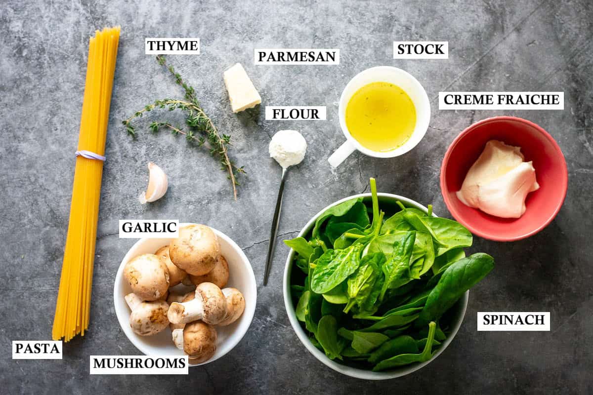 Labelled ingredients for spianch and mushroom pasta with creme fraiche sauce on a greay surface.