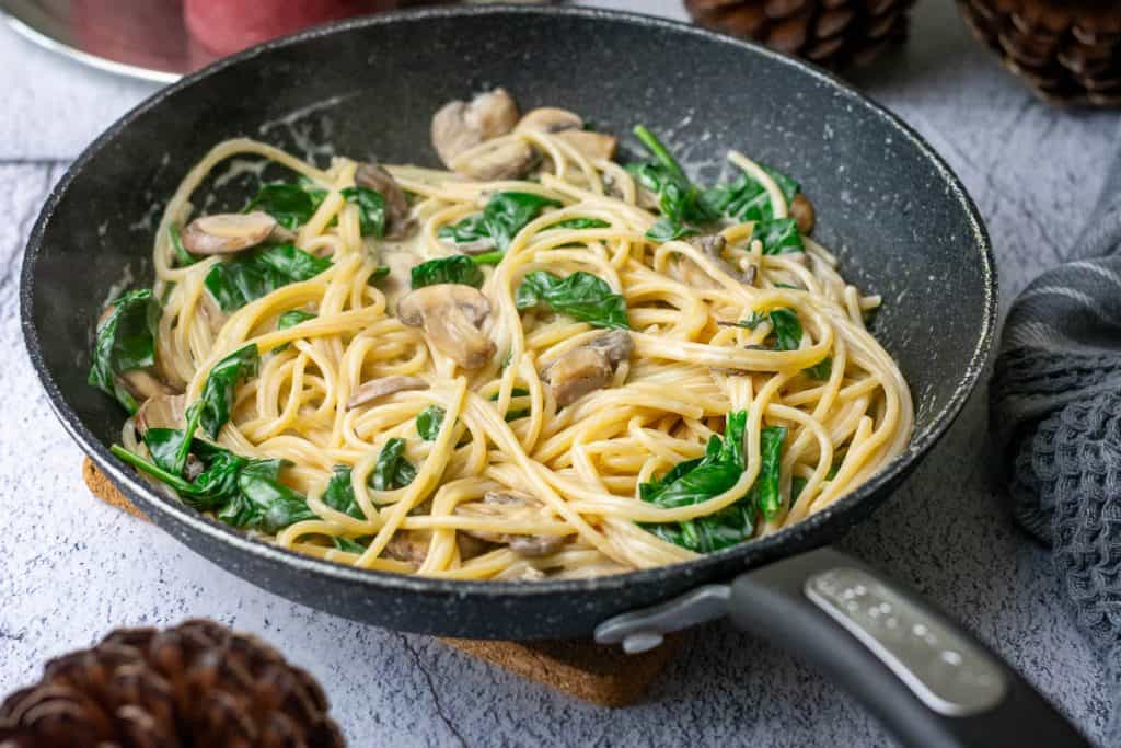 Creamu mushroom and spinach pasta in a frying pan ready to be served.