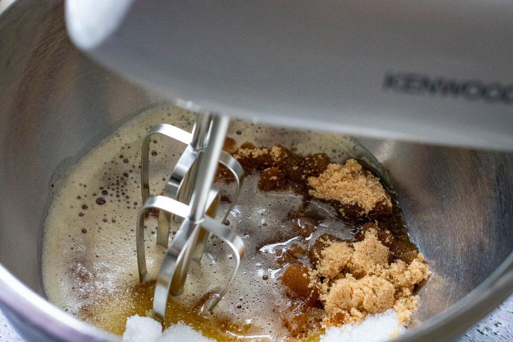 Beating butter and sugar using an electric handheld mixer in a large mixing bowl.