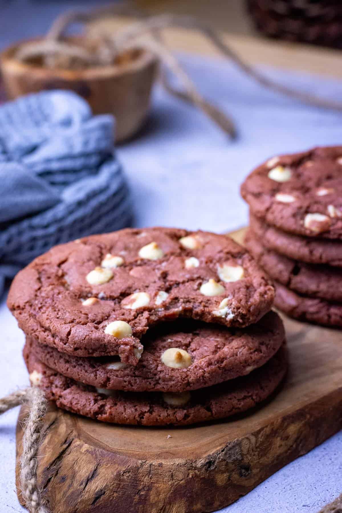 Stacks of sourdough red velvet cookies with one biten into.