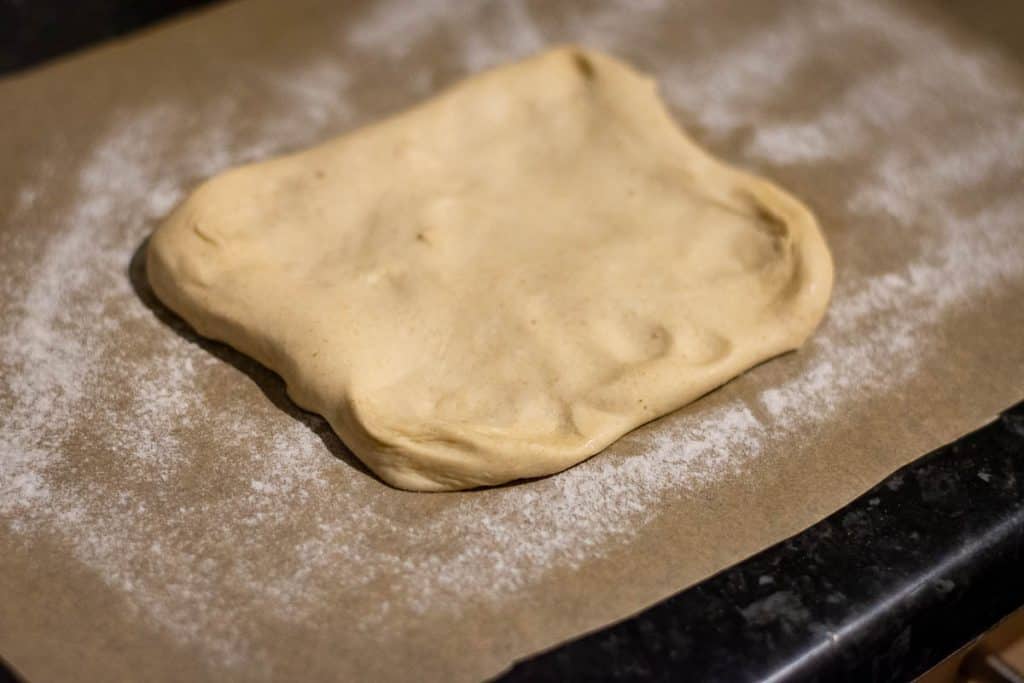 Sourdough discard flammkuchen dough on a floured piece of parchment paper.