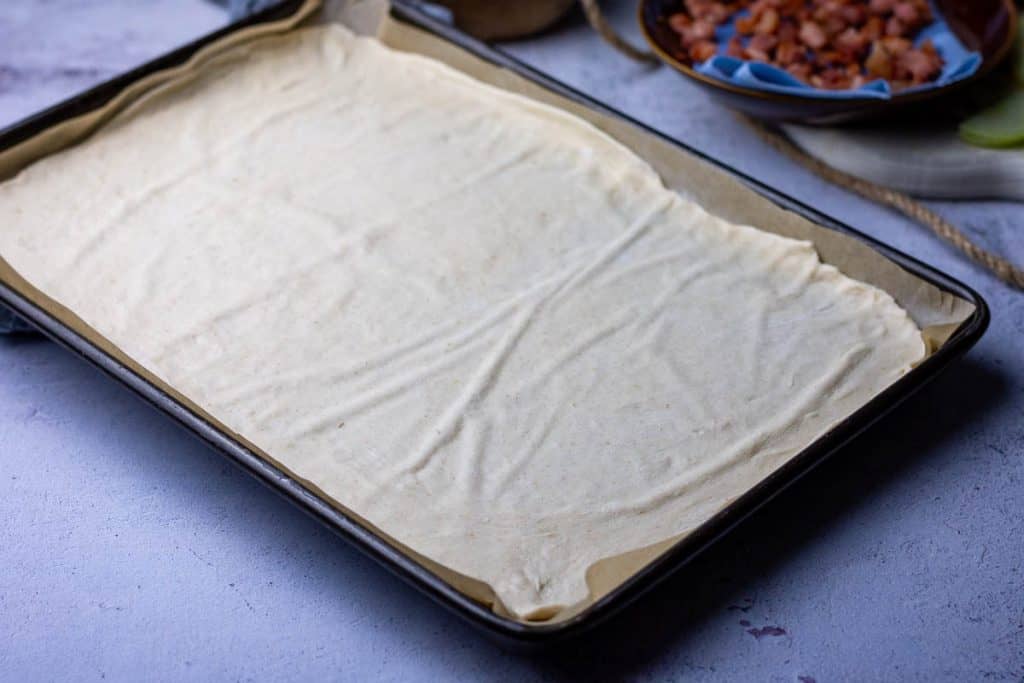 Sourdough rolled out thinly on a baking sheet.