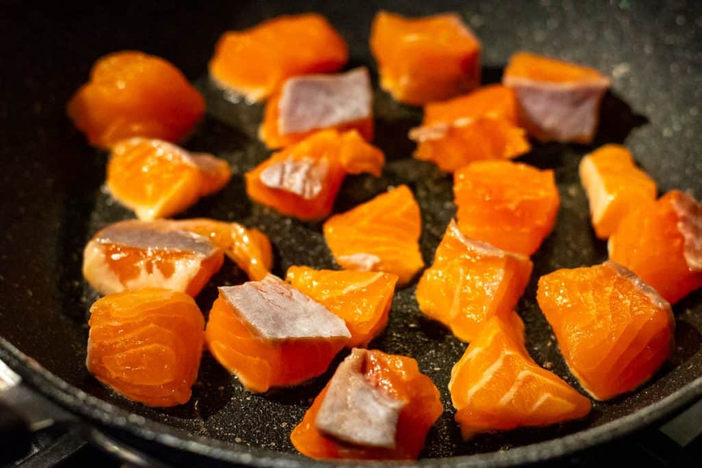 Cubed salmon in a frying pan.