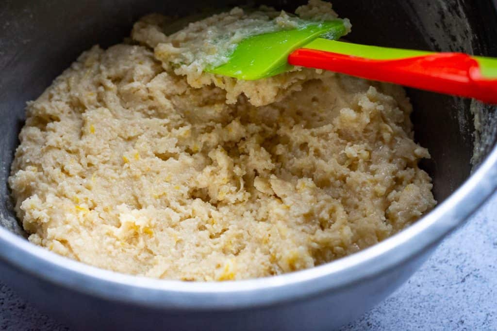 Sourdough lemon crinkle cookie dough being mixed in a large metal bowl.