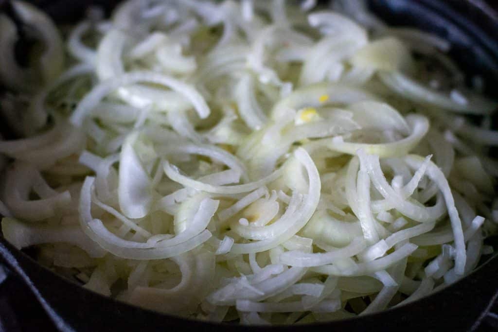 Sliced onion in a cst iron skillet.