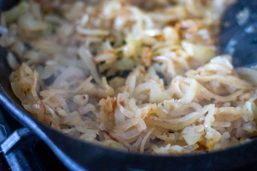 Onion caramelising and browning in a pan.
