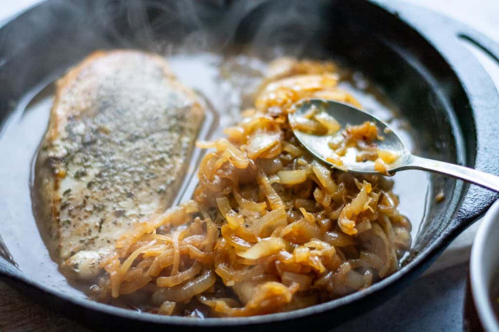 Caramelised onion being spooned on top of the chicken breasts.
