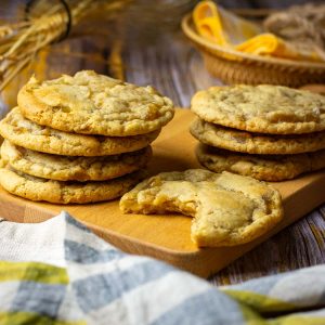 Stacks of soudough ginger cookies on a wooden board with one sourdough cookie missing a bite.