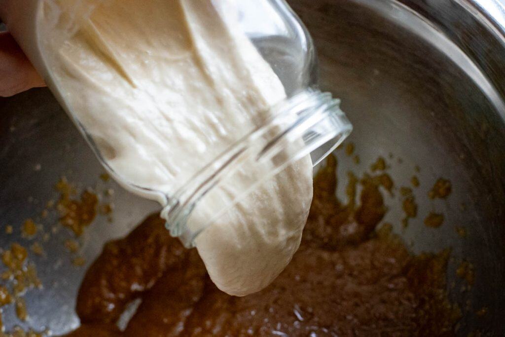 Sourdough discard being added to the sugar, butter and egg yolk mixture.